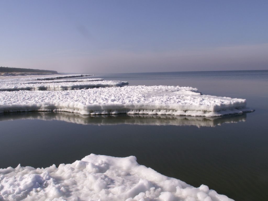 Flauta. Przy brzegu wcinające się w morze niczym pomosty, nagromadzone i zrównane pokłady lodu.