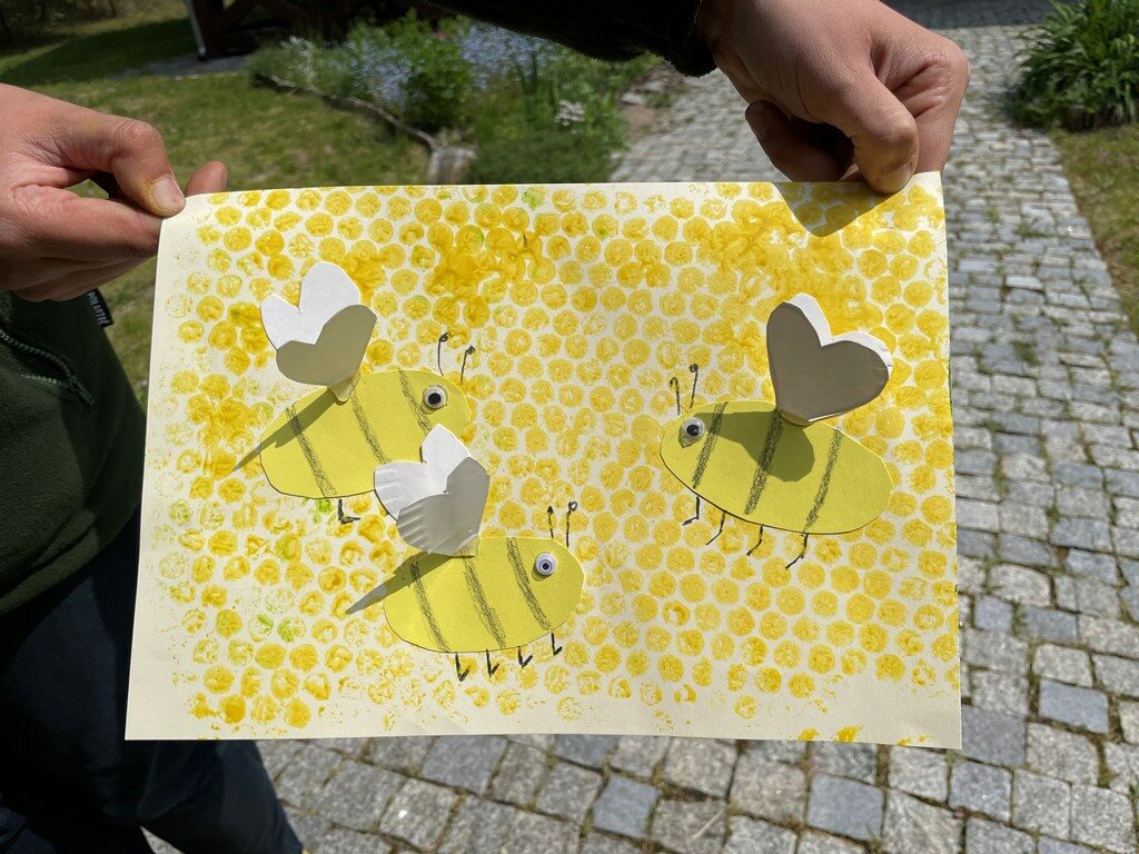 Praca plastyczna w kolorze żółtym, przyklejone do dużej kartki małe kartki w kształcie pszczół.